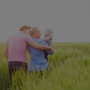 Family Walking Through Field of Green Grass